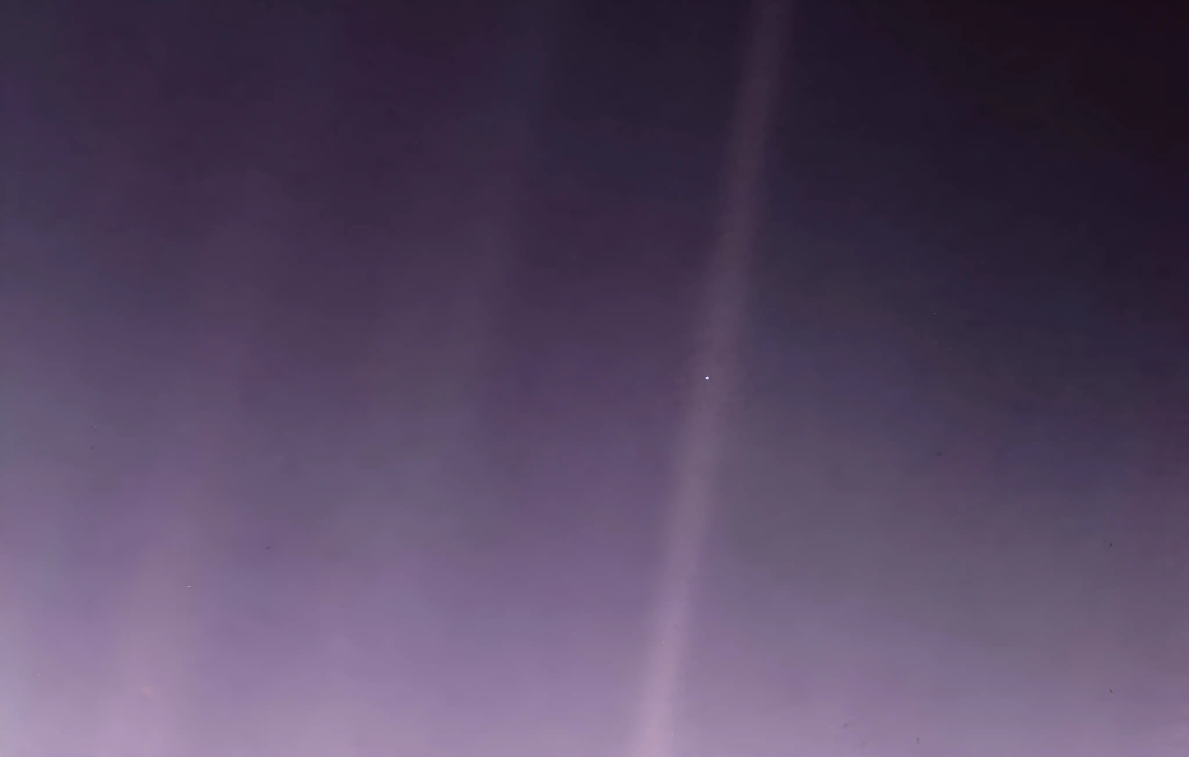 A deep purple and slightly grainy cosmic sky texture is subtly illuminated with lighter vertical bands of light. A small white pinpoint of light is clearly visible near the center of the image. The colors get darker towards the bottom and right sides. There is a very slight gradient.