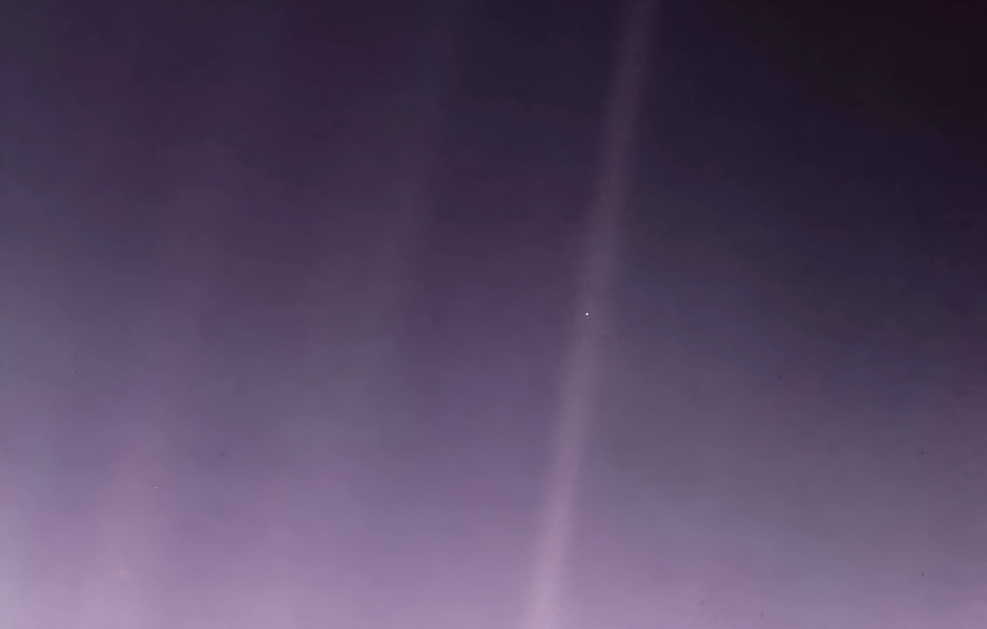 A deep purple and slightly grainy cosmic sky texture is subtly illuminated with lighter vertical bands of light. A small white pinpoint of light is clearly visible near the center of the image. The colors get darker towards the bottom and right sides. There is a very slight gradient.